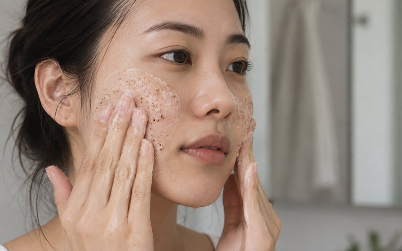 Woman-using-exfoliating-scrub-on-face